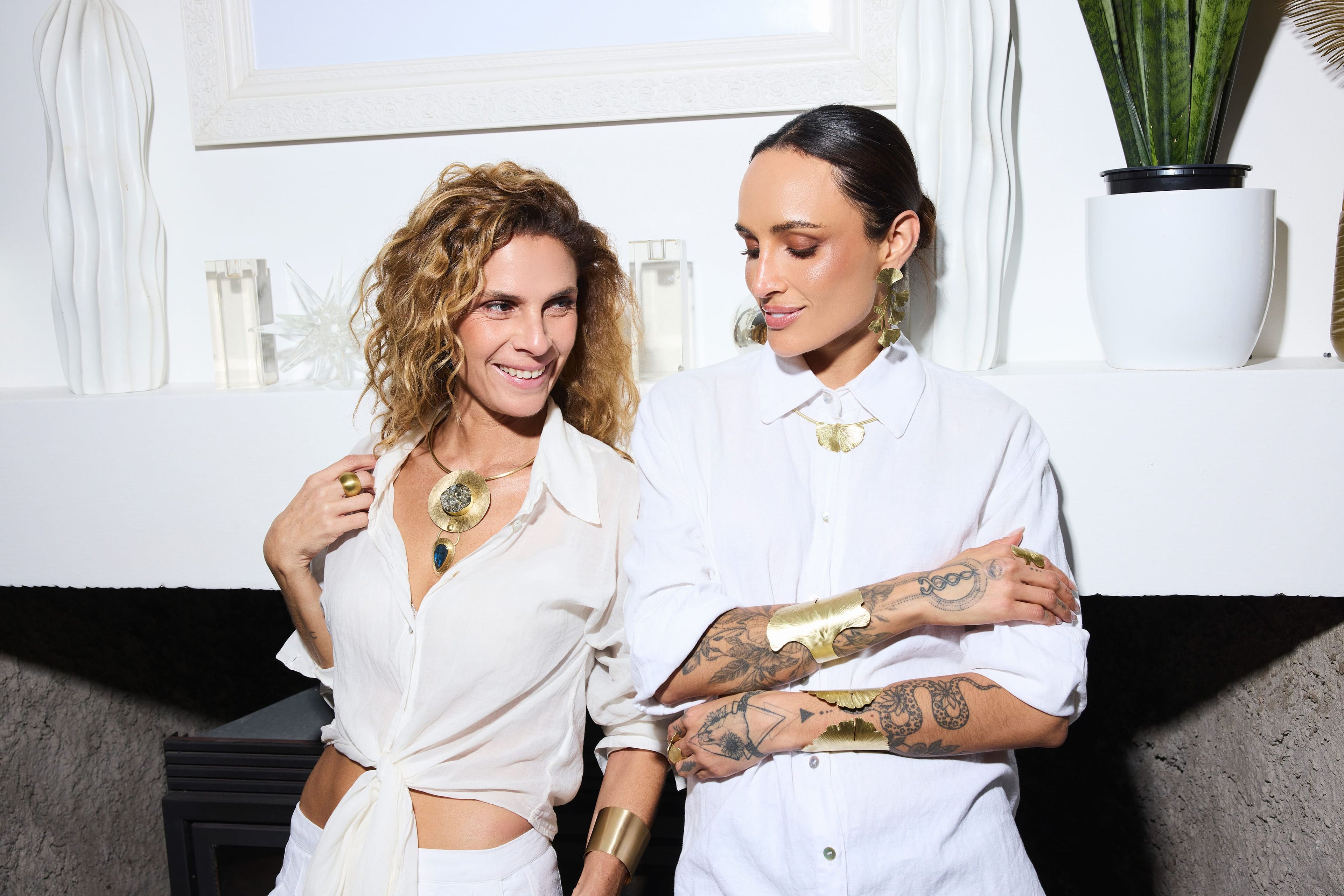Mujeres usando joyas de bronce hechas a mano de Veronica Silva, incluyendo collares, aros, anillos y pulseras, en un ambiente moderno y elegante.